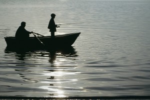 Father with son (10-11) in small boat fishing
